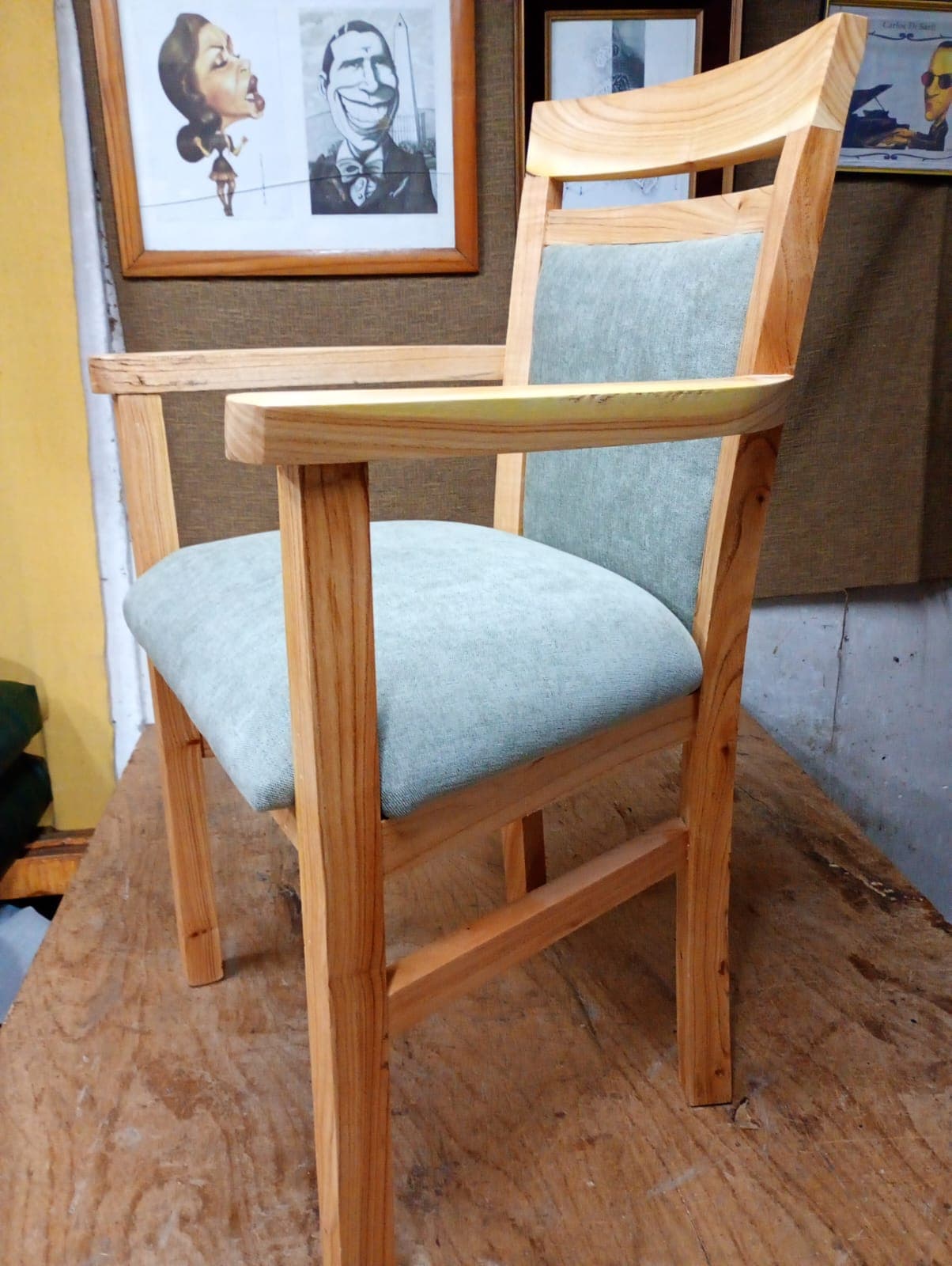 Sillón de madera clara con apoyabrazos, asiento y respaldo tapizados en tela verde agua